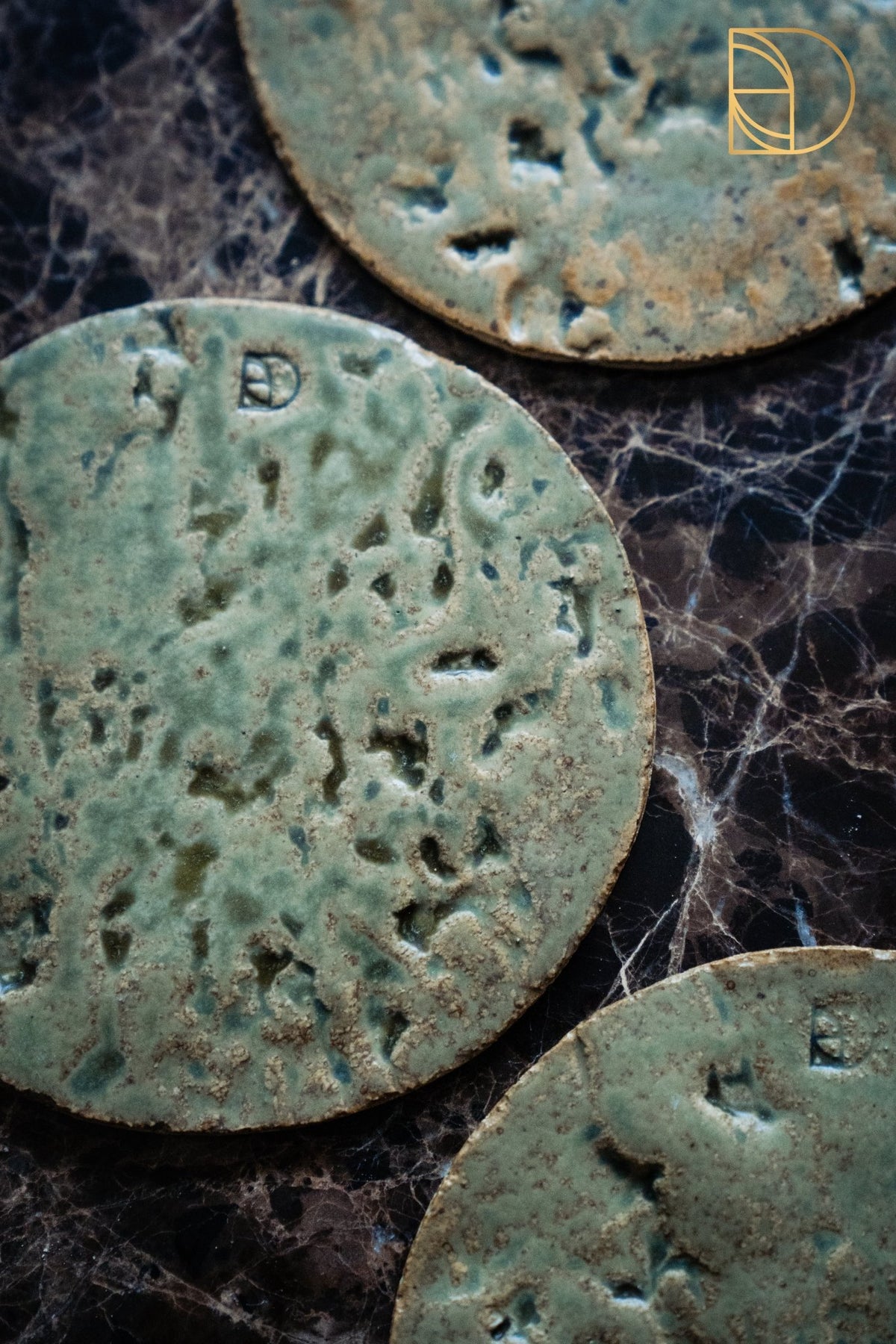 Drie groene keramieken bordjes met schorsrelief op een donkere marmeren ondergrond.