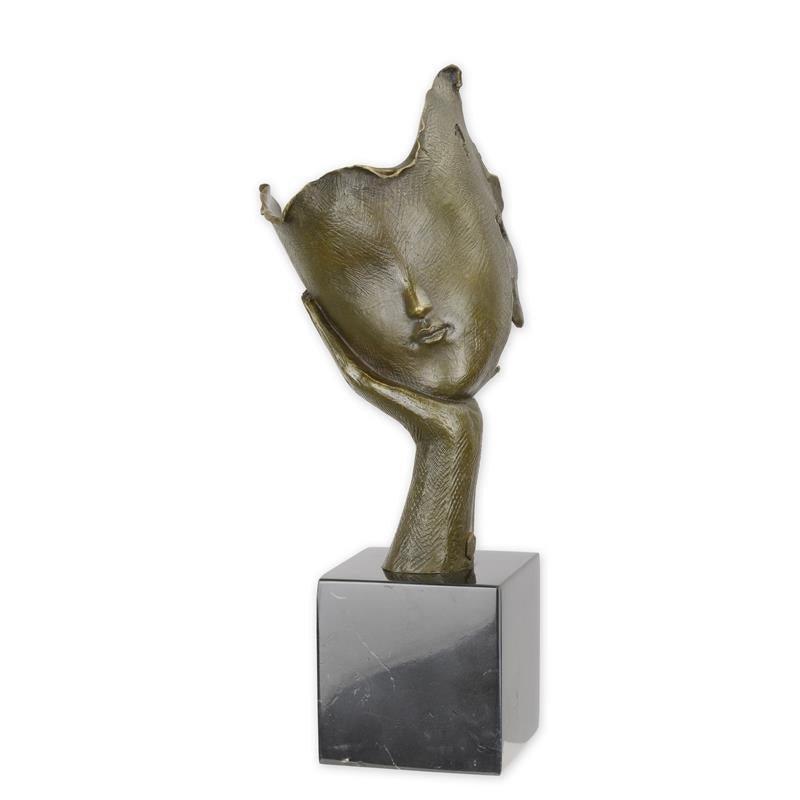 Een Bronzen sculptuur van een Dromende Gezicht in een hand op voetstuk ter decoratie voor in huis.