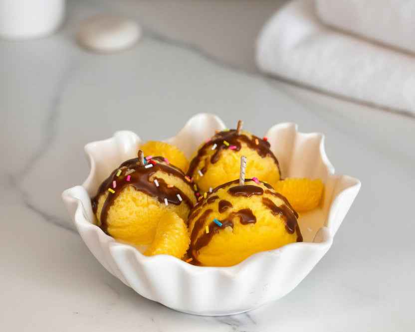 Dessertkaars in een witte geschulpte coupe met partjes sinaasappel van was op marmer