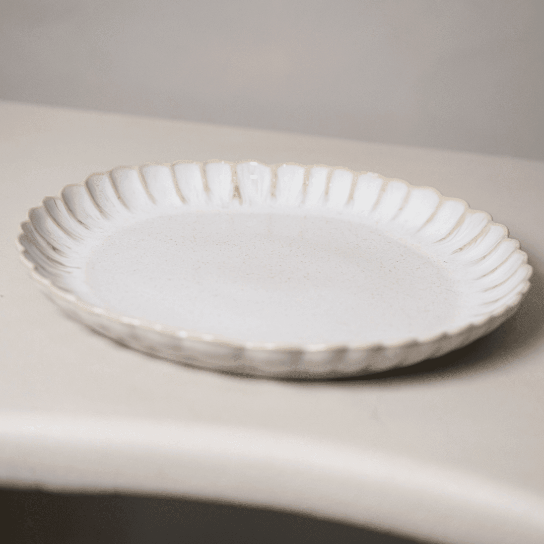 Gebroken wit dinerbord schuin van boven, met brede geribbelde rand.
