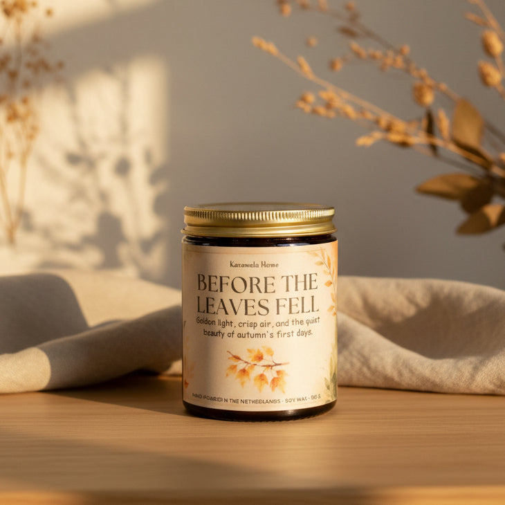 Geurkaars in een amberkleurige glazen pot met gouden schroefdeksel en crème etiket bij droogbloemen