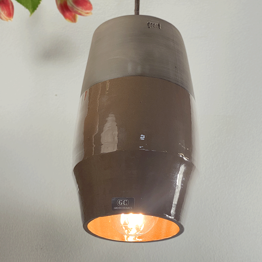 Ovale keramieken hanglamp met chocoladebruin glazuur en brandende lamp.