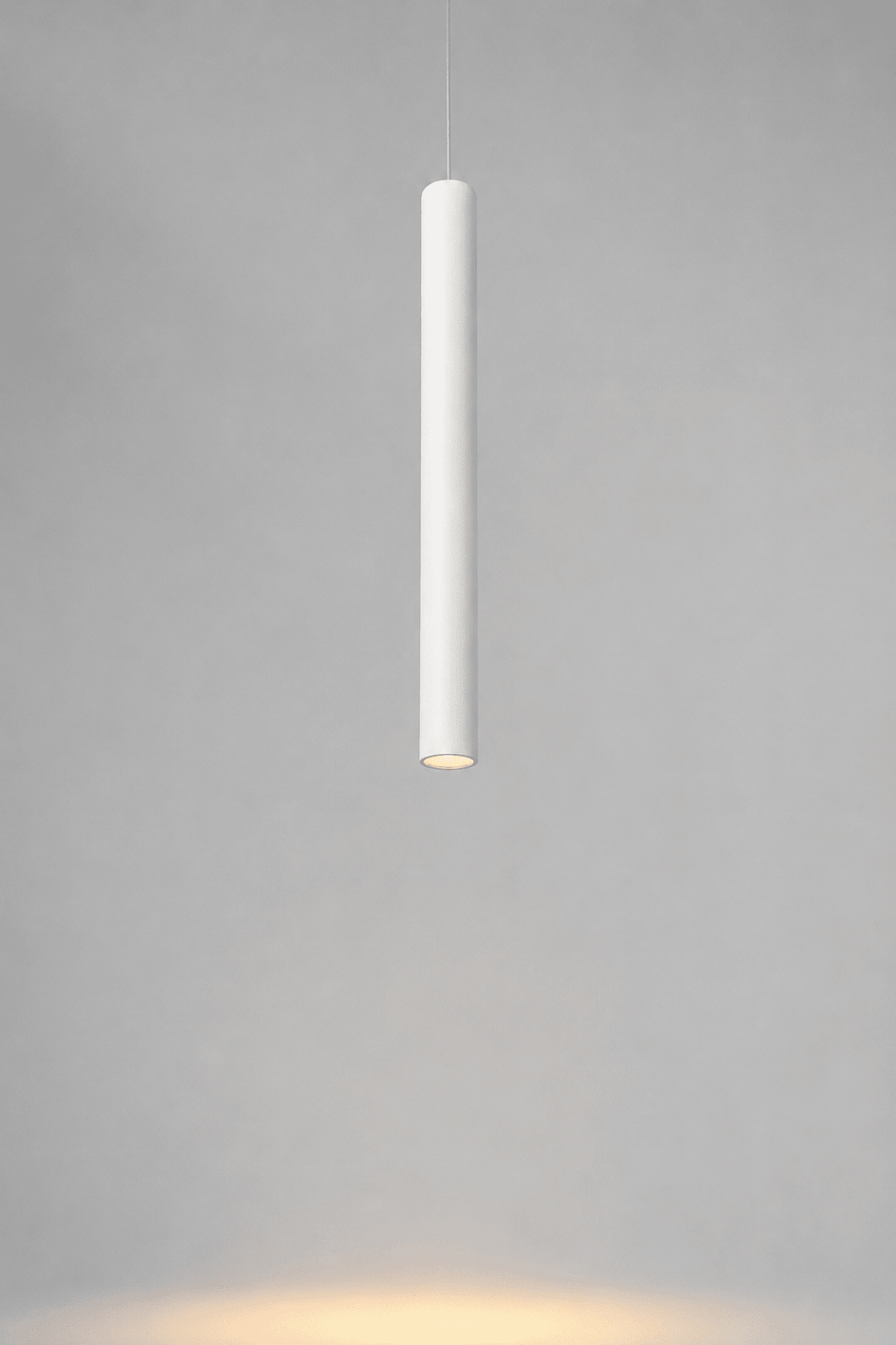 Witte cilindrische hanglamp aan een dun snoer.