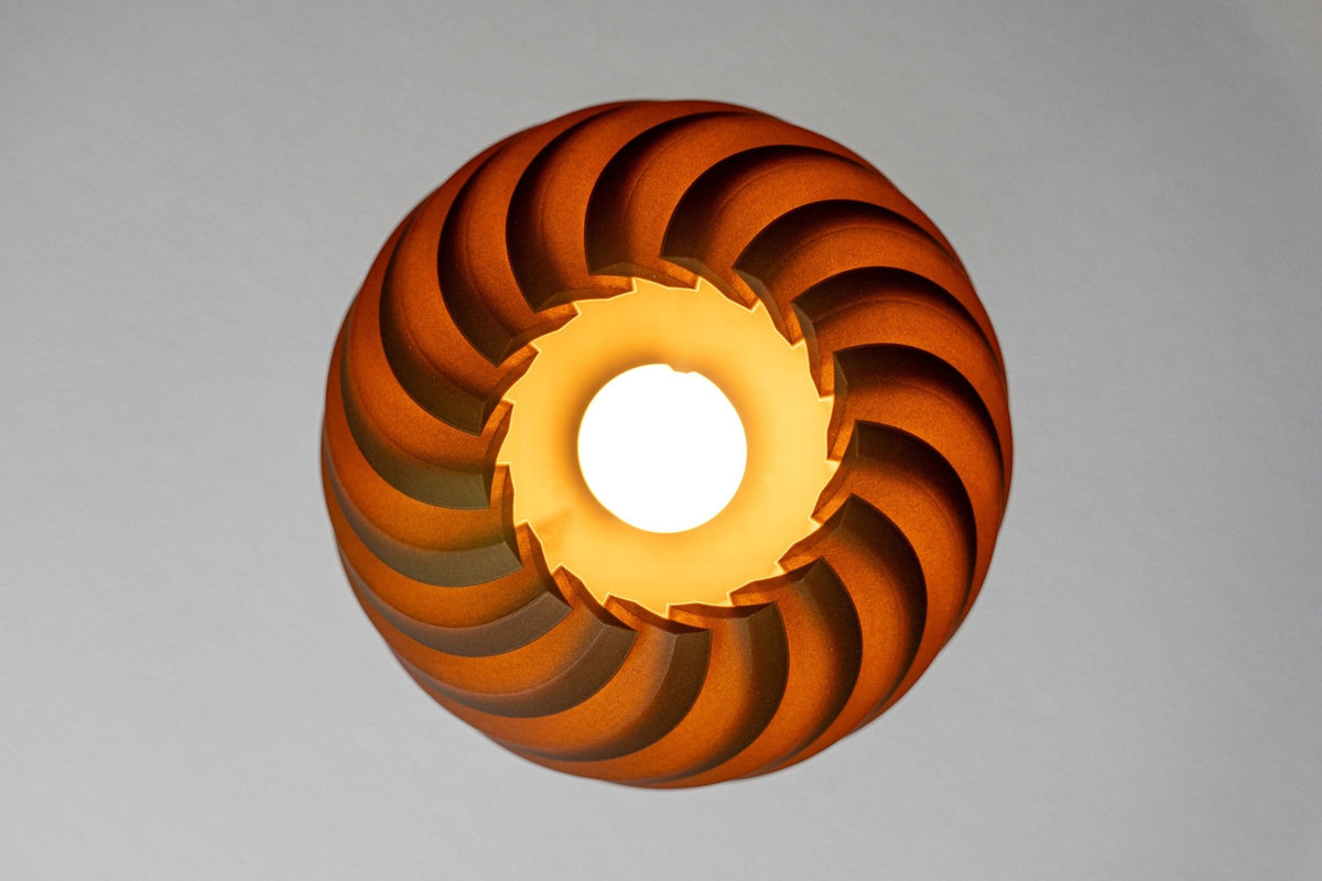 Donkerbruine bolvormige lampenkap van onderaf met een brandende lamp in de opening.