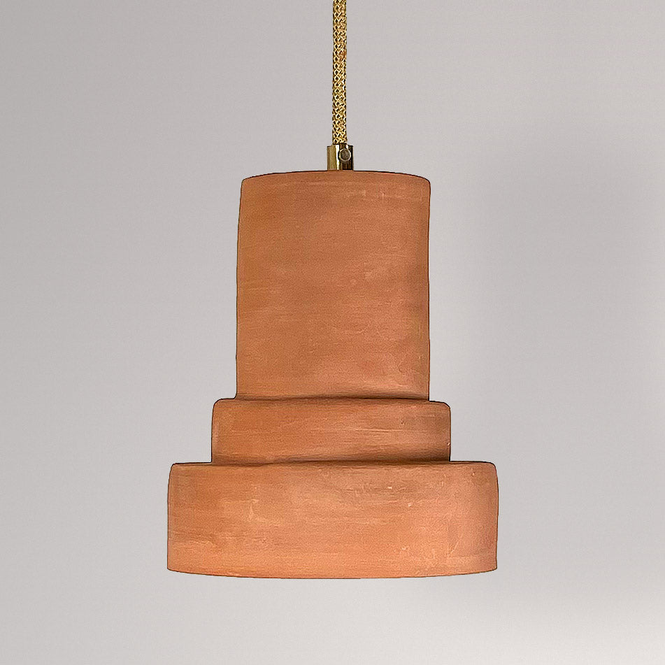 Getrapte keramieken hanglamp in terracotta aan een goudkleurig textielsnoer.