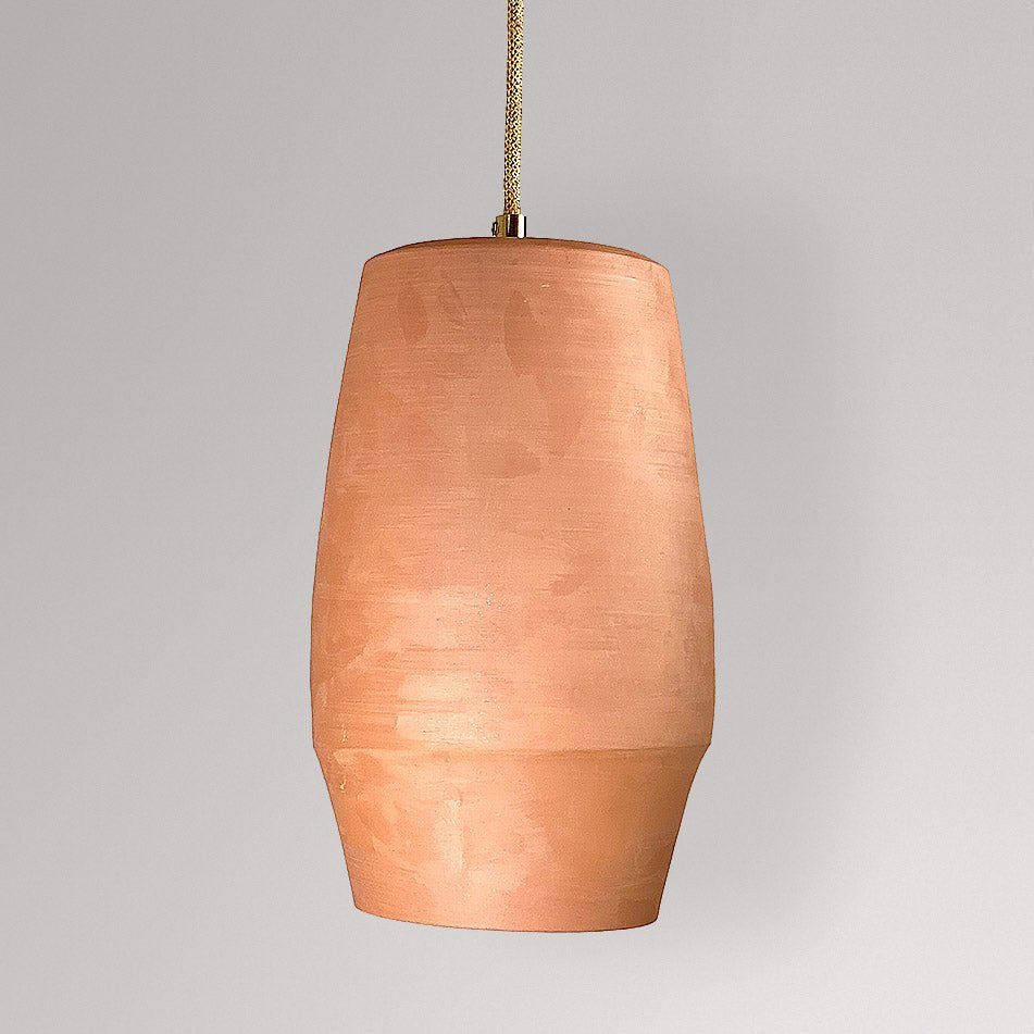 Langgerekte ovale keramieken hanglamp in terracotta aan een goudkleurig snoer.