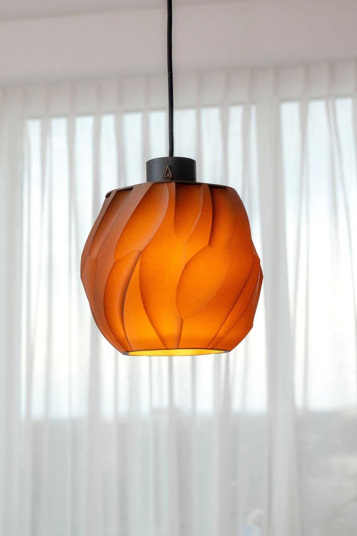 Bolvormige hanglamp met diep reliëf, warm oplichtend voor een raam bij zonsondergang.