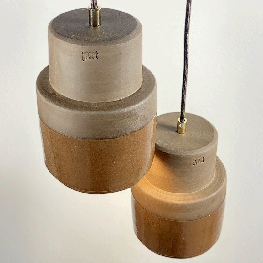Drie keramieken hanglampen met grijze bovenkant en chocoladebruin glazuur.