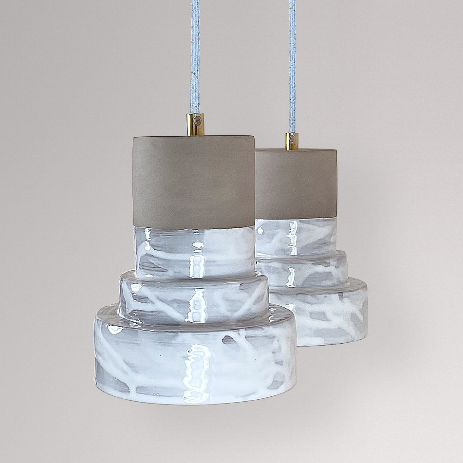 Twee getrapte keramieken hanglampen met wit gemarmerd glazuur.