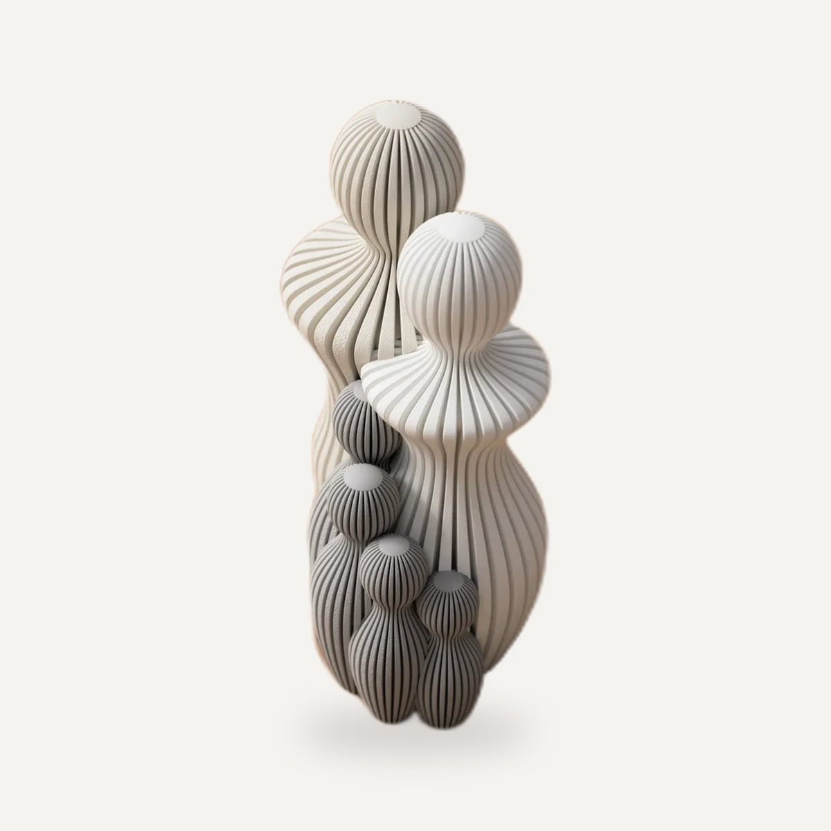Abstract beeldje met geribbelde figuren in crème en grijs naast elkaar.