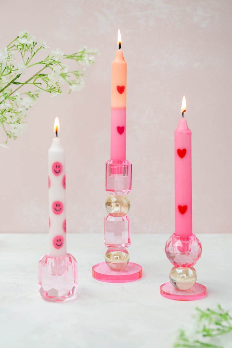 Deze elegante glazen kandelaar combineert een verfijnde roze tint met een glanzende gouden bol, waardoor een speels en stijlvol geheel ontstaat.