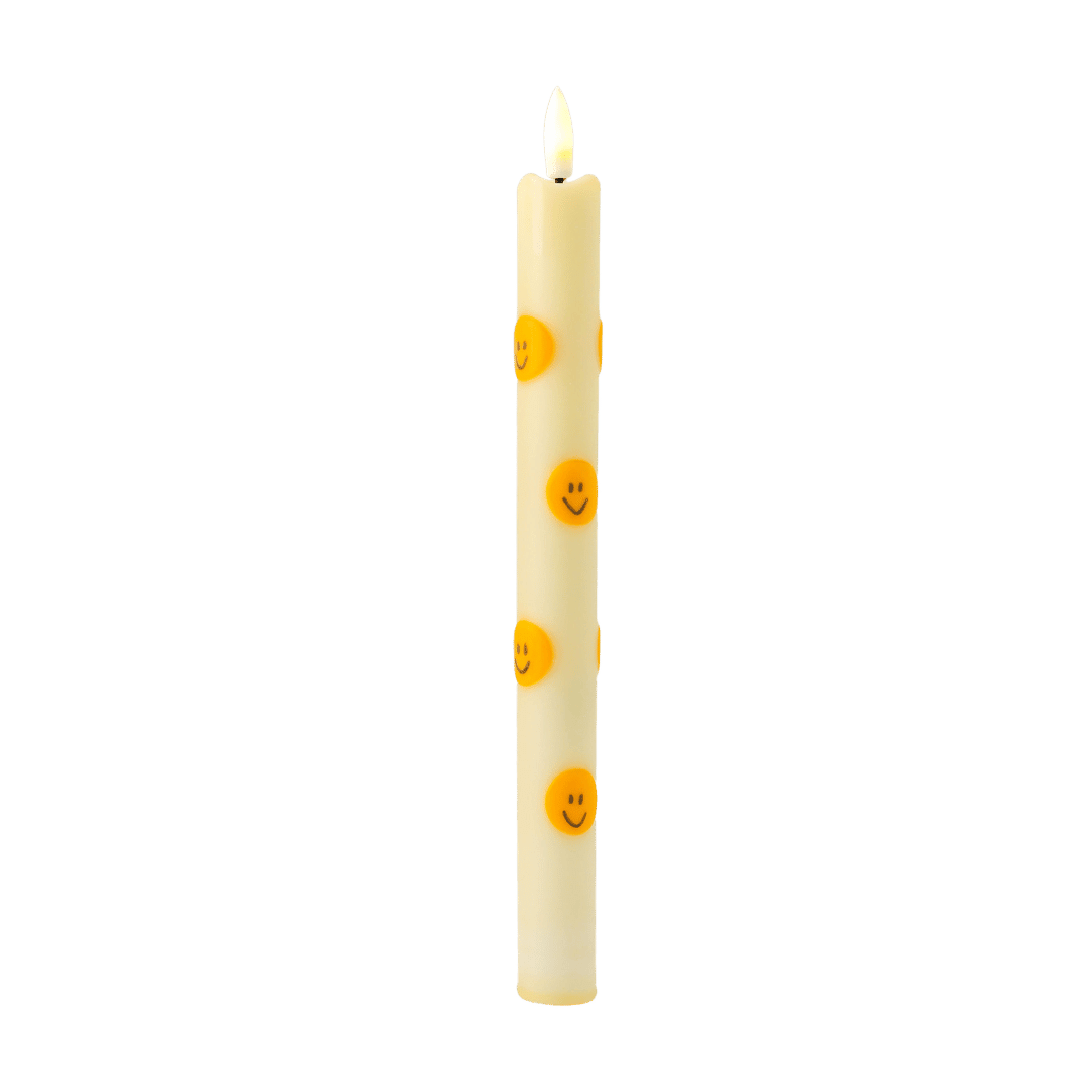 De slanke kaars heeft een zachte lichte tint en is versierd met opvallende oranje smileys, waardoor hij direct een positieve en eigentijdse uitstraling krijgt.