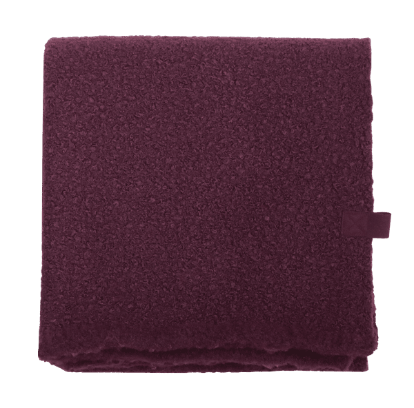 Opgevouwen plaid van diep aubergine bouclé met korrelige, teddyachtige structuur.