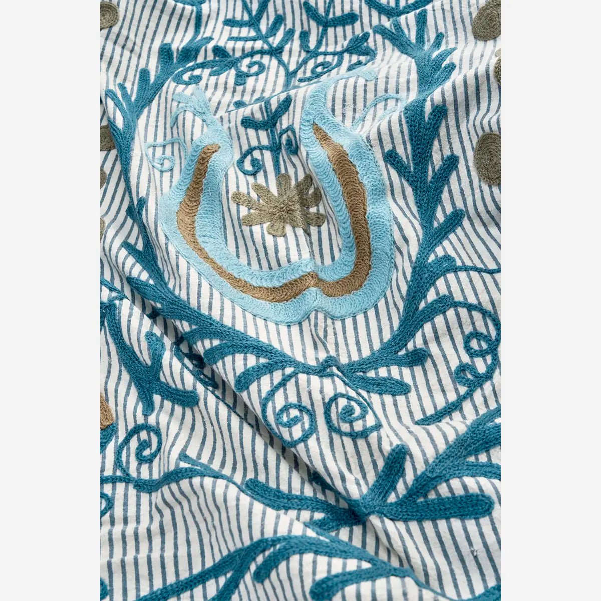 De kleuren blauw, greige, zand en off-white zorgen voor een harmonieus geheel, terwijl het reliëf van het borduurwerk diepte en karakter toevoegt.