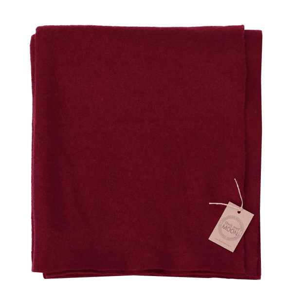 Opgevouwen plaid van diep bordeauxrode gekookte wol met een gemêleerde structuur.