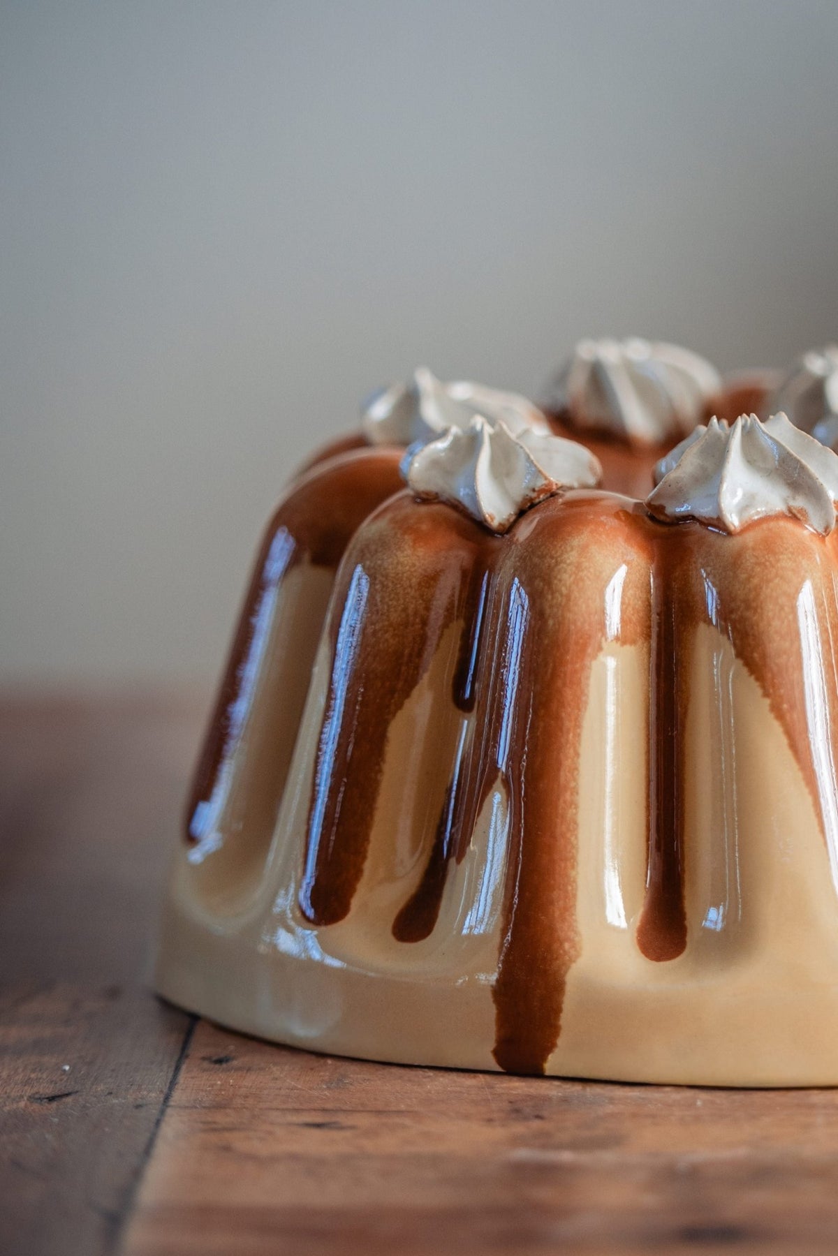 Detail van een keramieken puddingvorm met glanzend karamelglazuur en slagroomtoefjes.