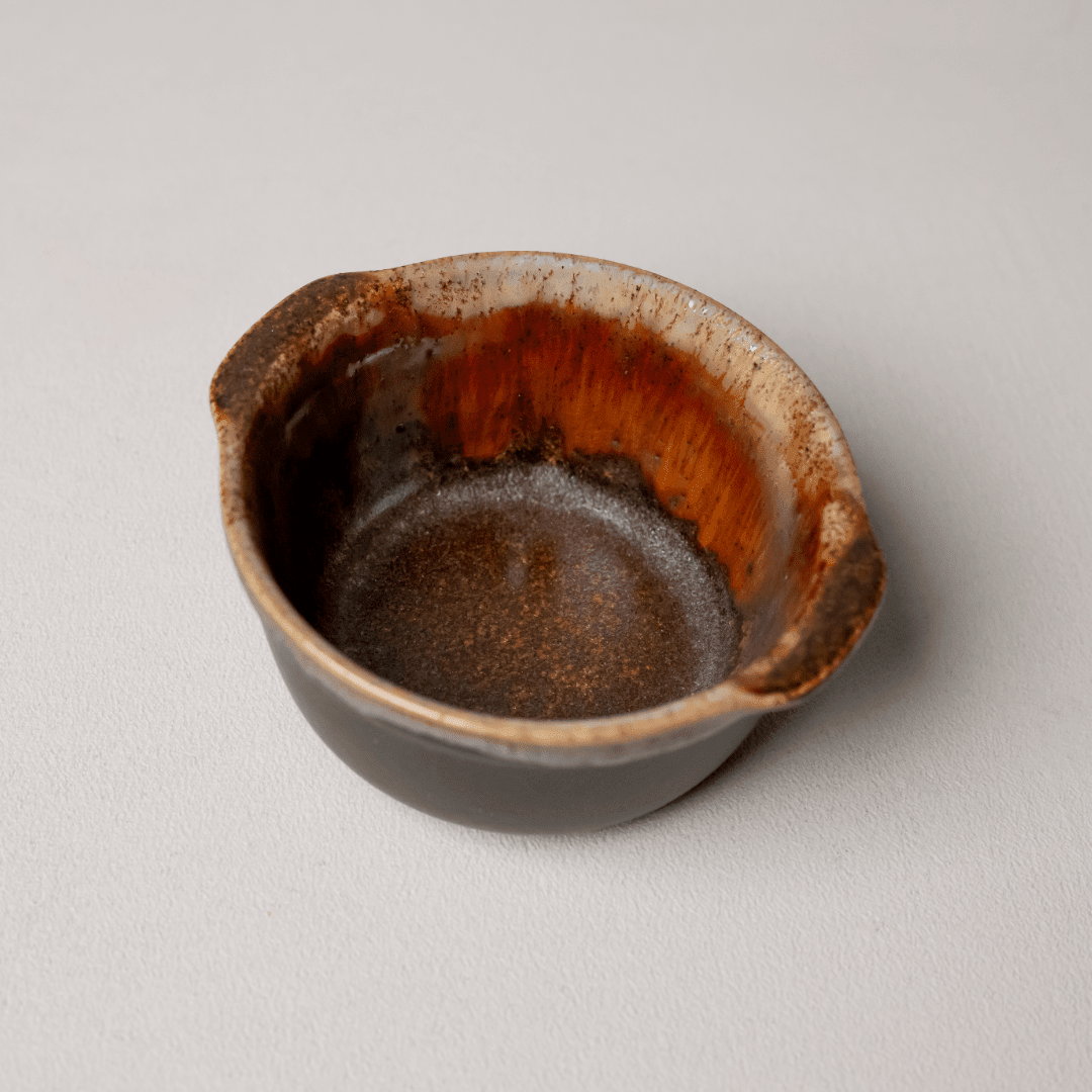 Schaaltje van boven: een ring roestbruin glazuur rond een grijsbruine bodem.