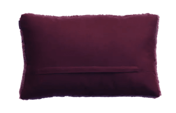 Achterzijde van het aubergine bontkussen: effen stof met een horizontale sluiting.