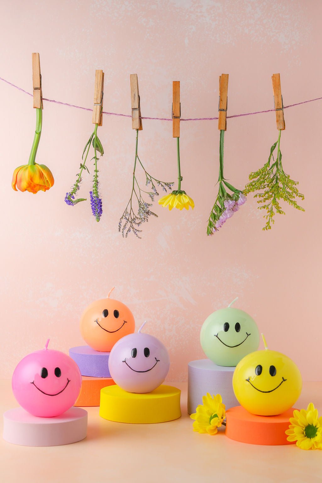 Een handgemaakte bolkaars rond met een zwart smiley gezicht erop.