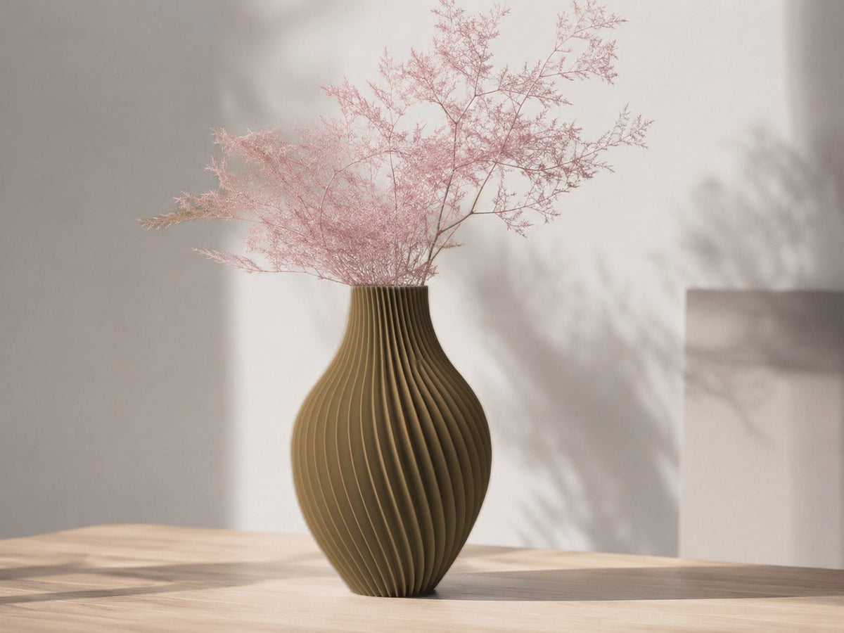 Buikige vaas met gedraaide ribbels in goud, met roze droogtakken erin.