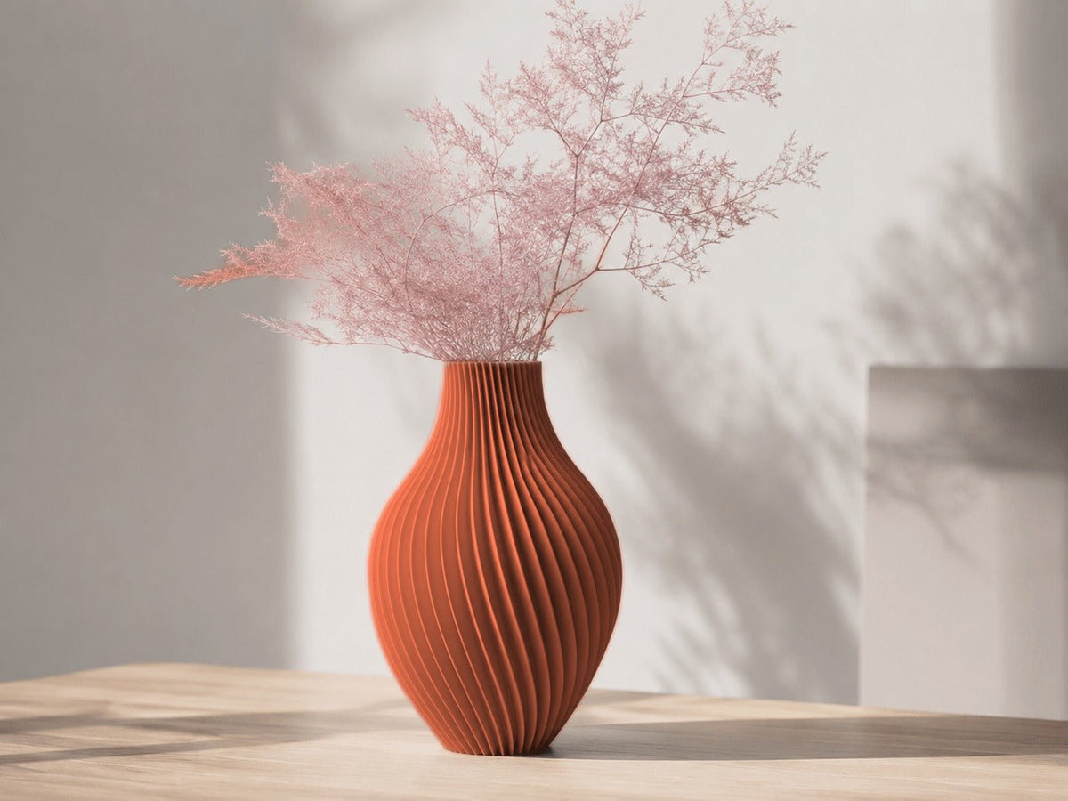 Buikige vaas met gedraaide ribbels in terracotta, met roze droogtakken erin.