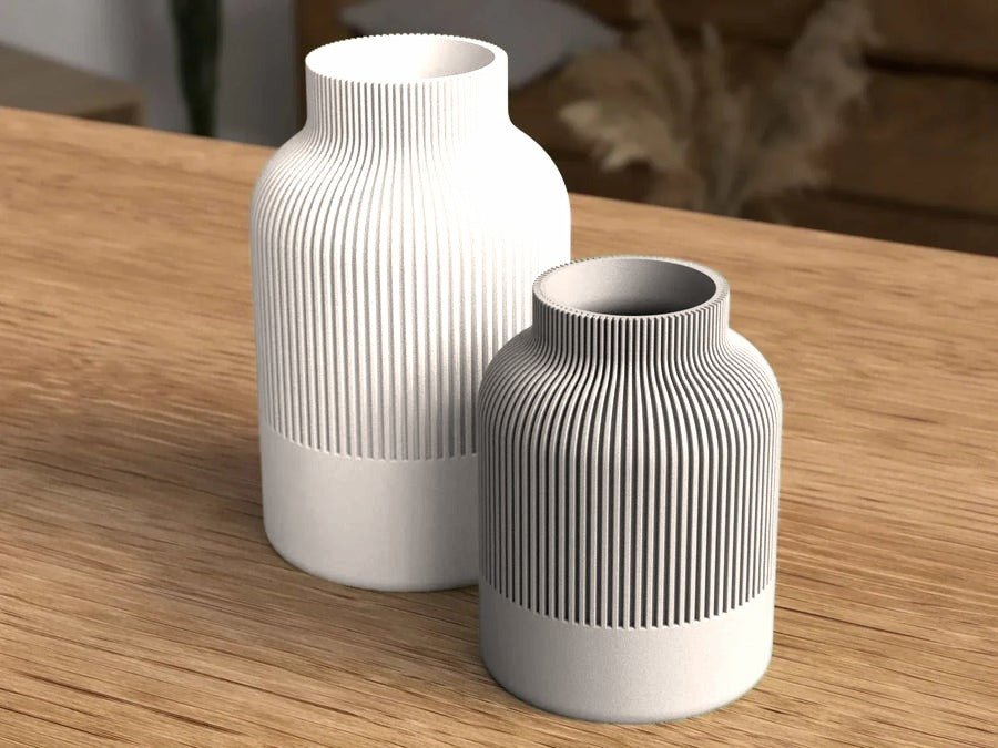 Twee rechte geribbelde vazen in crème naast elkaar op een houten tafel.