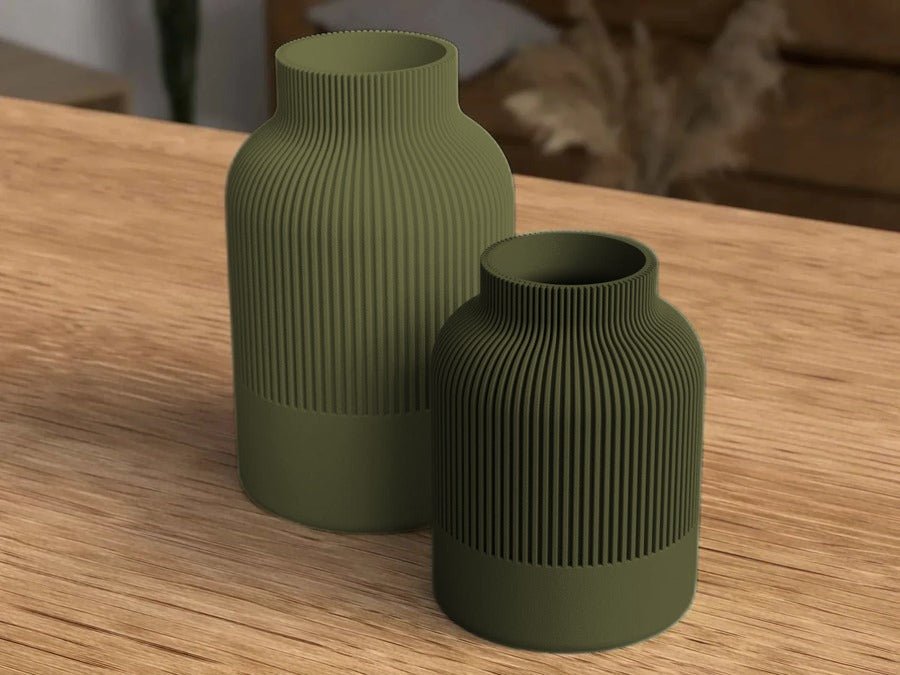 Twee rechte geribbelde vazen in legergroen naast elkaar op een houten tafel.