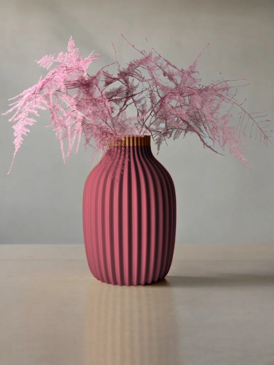 Vaas met verticale rimpelribbels in bordeaux, met roze droogtakken erin.