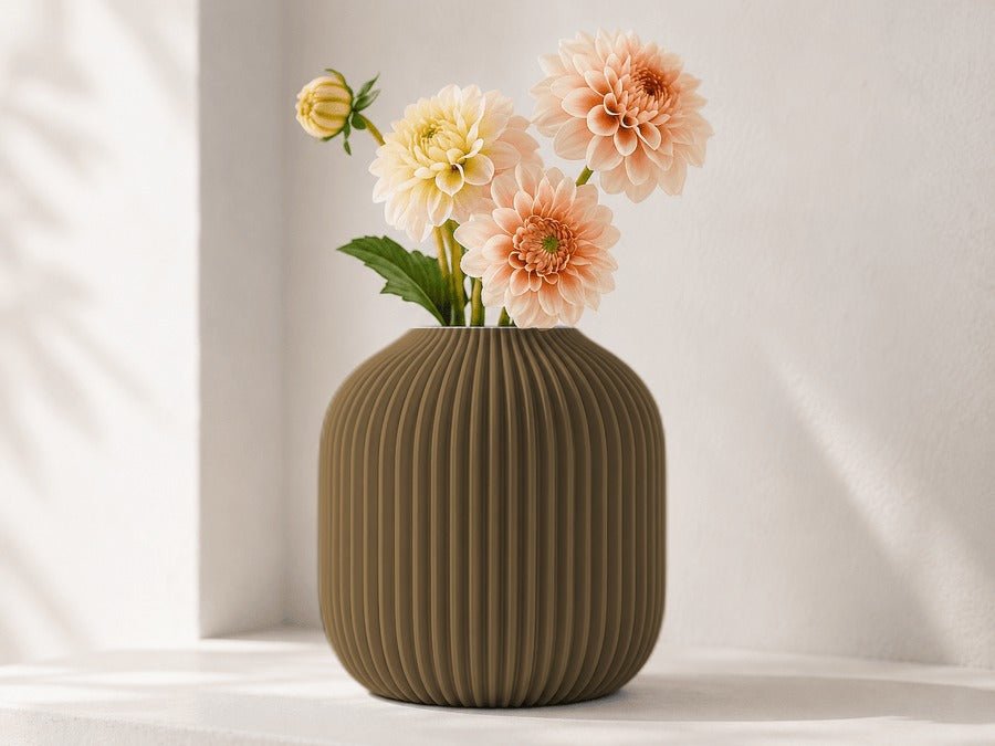 Ronde geribbelde vaas in goud met dahlia's erin.