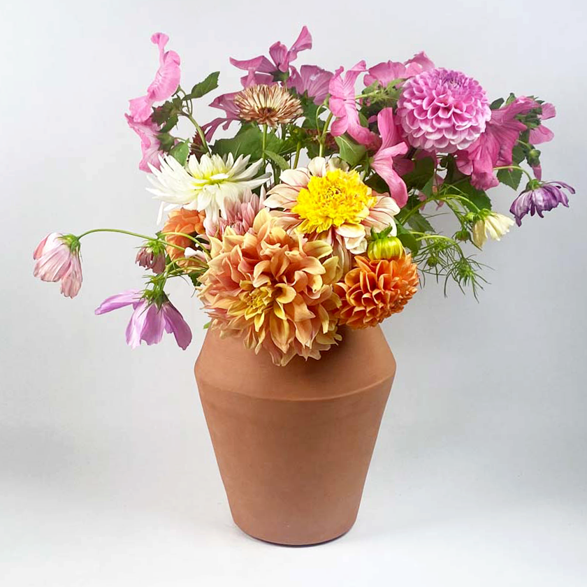 Terracotta keramieken vaas met een boeket dahlia's en zomerbloemen.