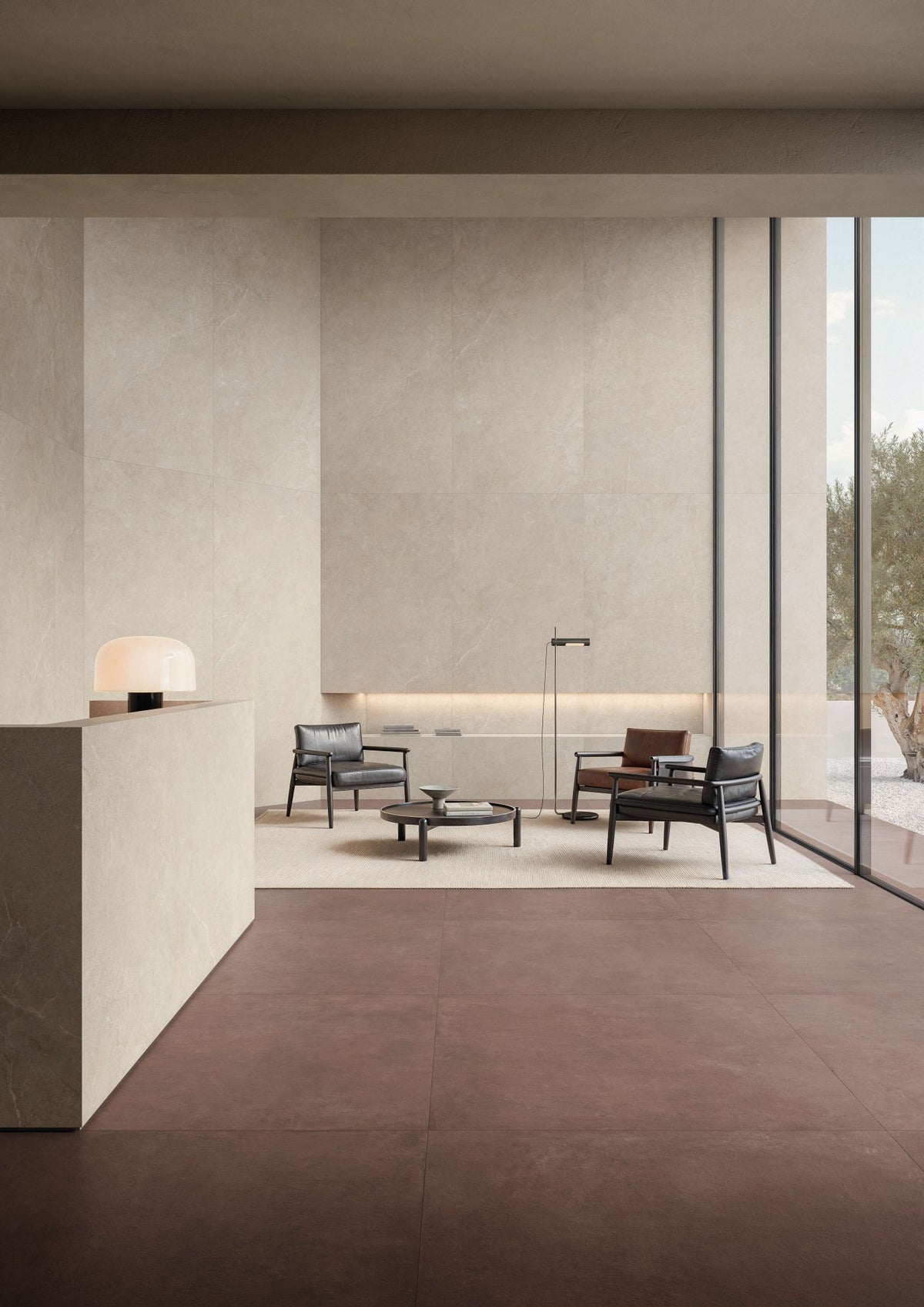 Ontvangstruimte met roestbruine betonlook vloer, lichte balie en houten fauteuil.