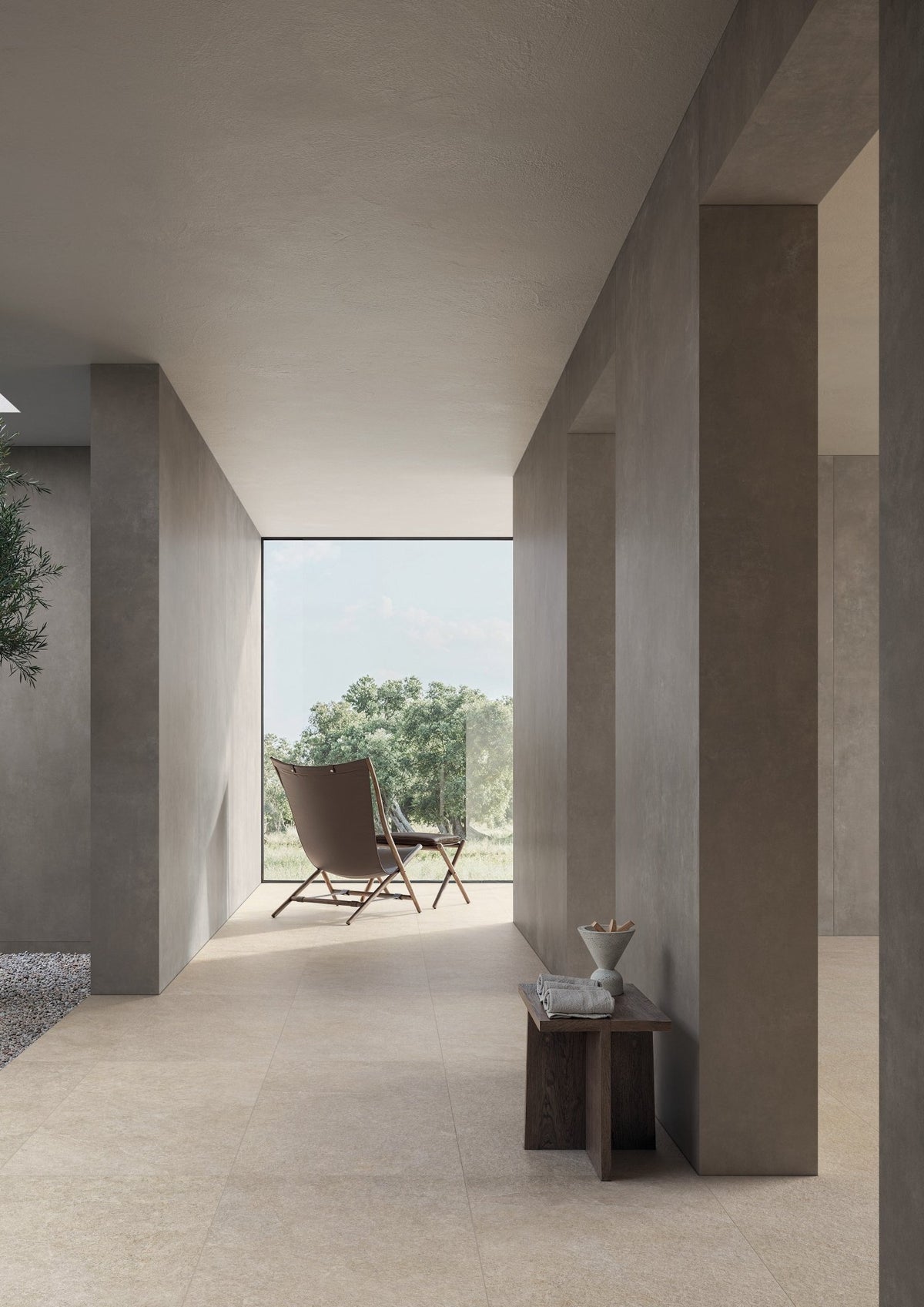 Gang met taupe betonlook vloer, beige wandtegels en doorkijk naar buiten.