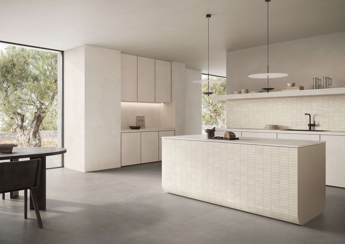 Keuken met kookeiland, eettafel en een lichte betonlook vloer.