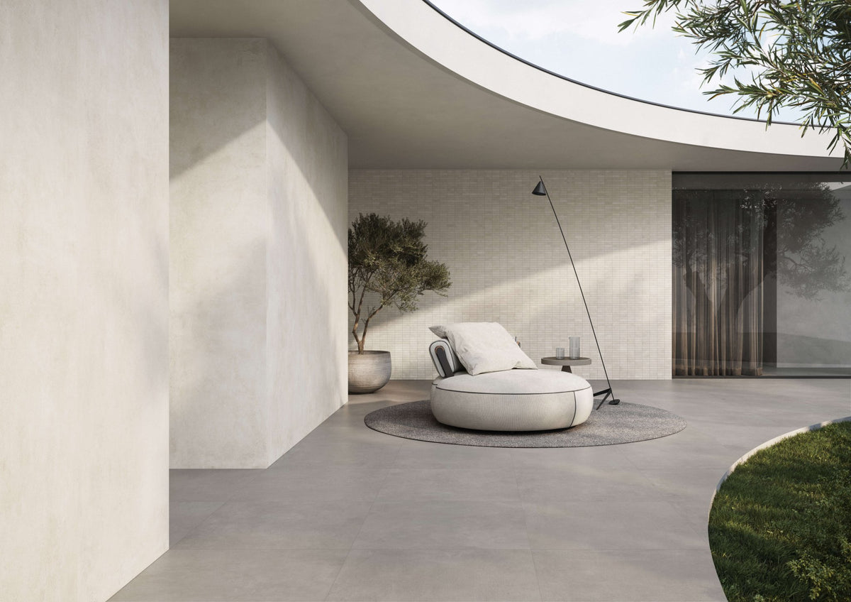 Lichte woonruimte met ronde loungestoel, gebogen wand en doorloop naar de tuin.