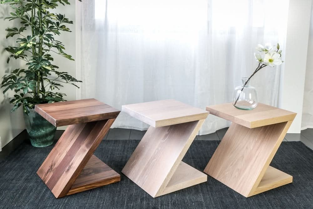 Drie Z-vormige houten bijzettafels naast elkaar in donker noten, wit en blank eiken