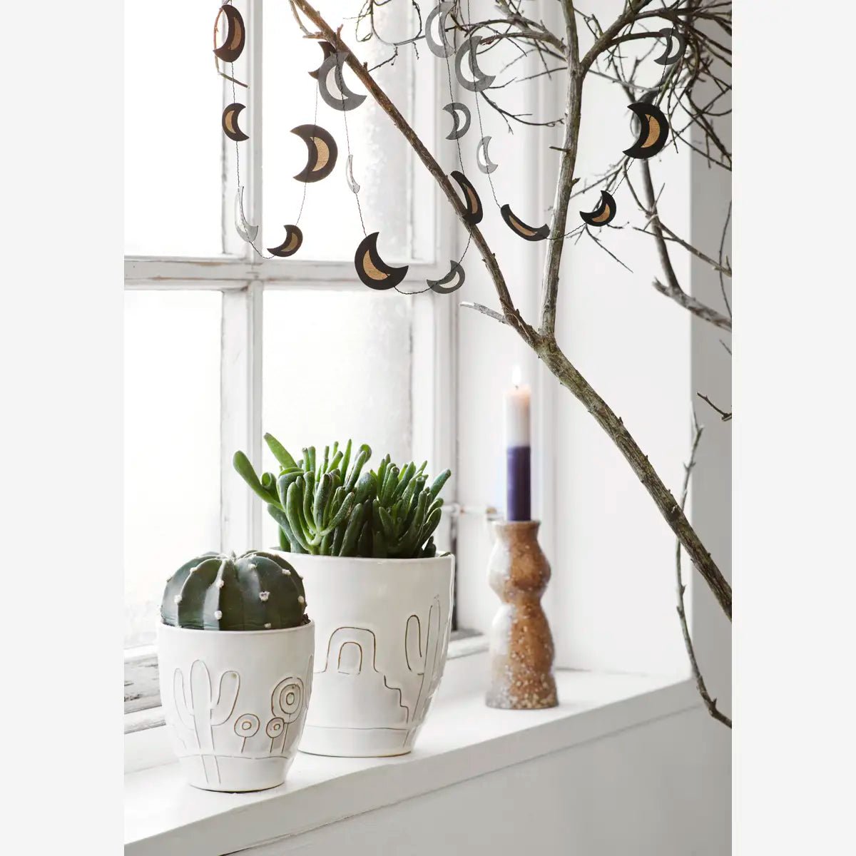 De potten zijn vervaardigd uit steengoed en uitgevoerd in een zachte witte glazuurlaag met een subtiel reliëf van cactussen en woestijnplanten.