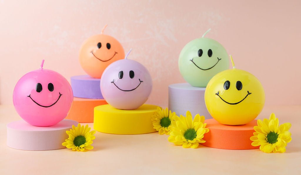 Een bolkaars in het mint met een zwart smiley gezicht erop. 