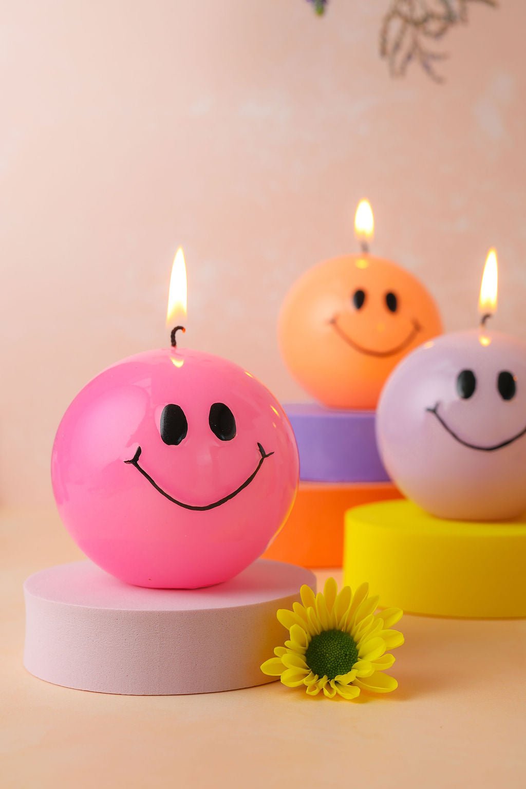 Handgemaakte bolkaarsen rond met een zwart smiley gezicht erop.