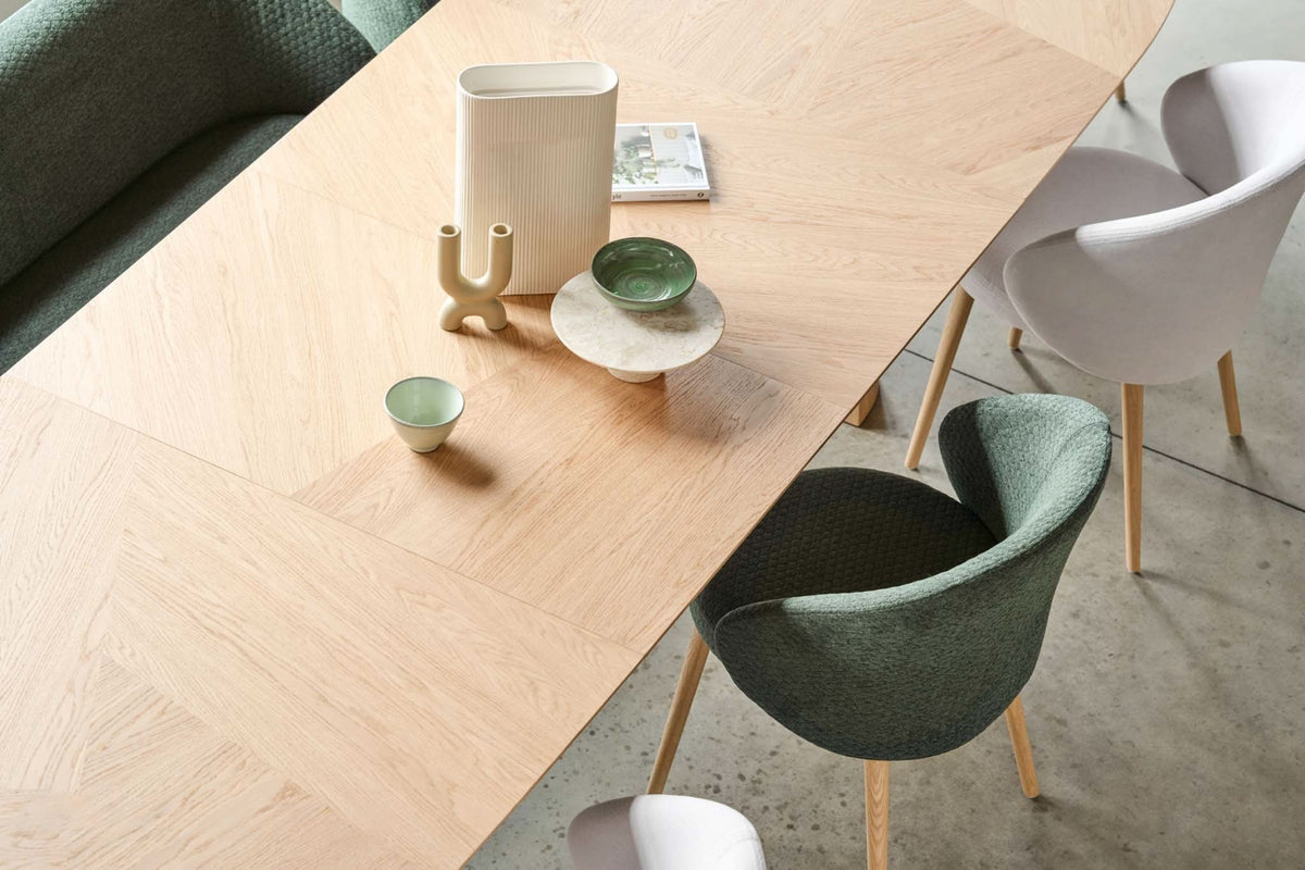Ovaal eiken tafelblad met een vaas, een schaaltje en glazen, met stoelen eromheen