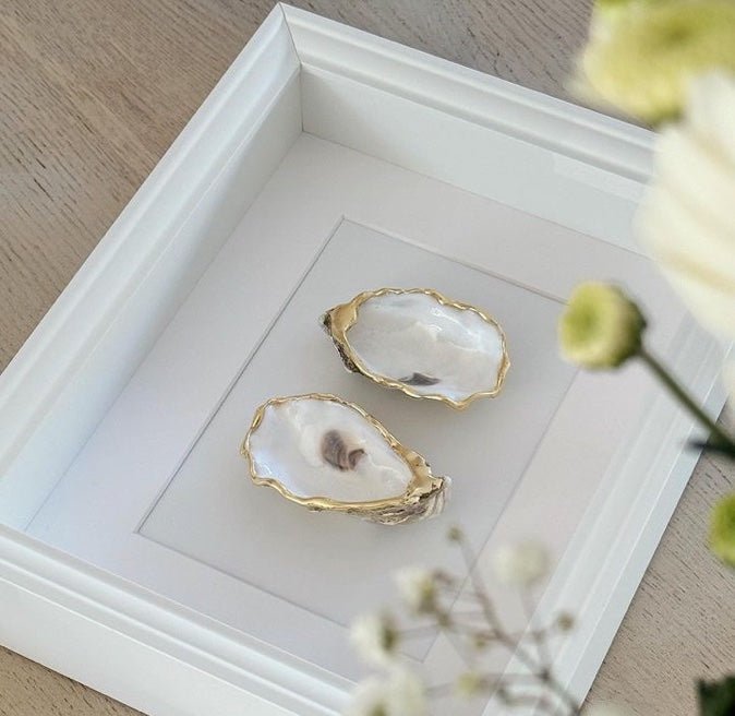  De combinatie van een echte oesterschelp met verfijnde gouden accenten en een stijlvolle roomwitte lijst zorgt voor een tijdloos kunstobject dat rust en luxe uitstraalt. 