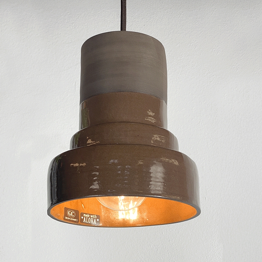 Getrapte keramieken hanglamp met chocoladebruin glazuur en brandende lamp.