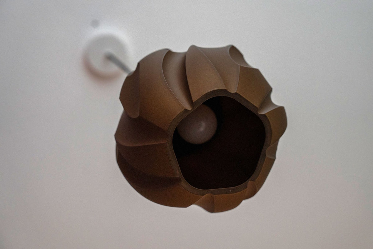 Donkerbruine bolvormige lampenkap van onderaf gezien met de lamp in de opening.