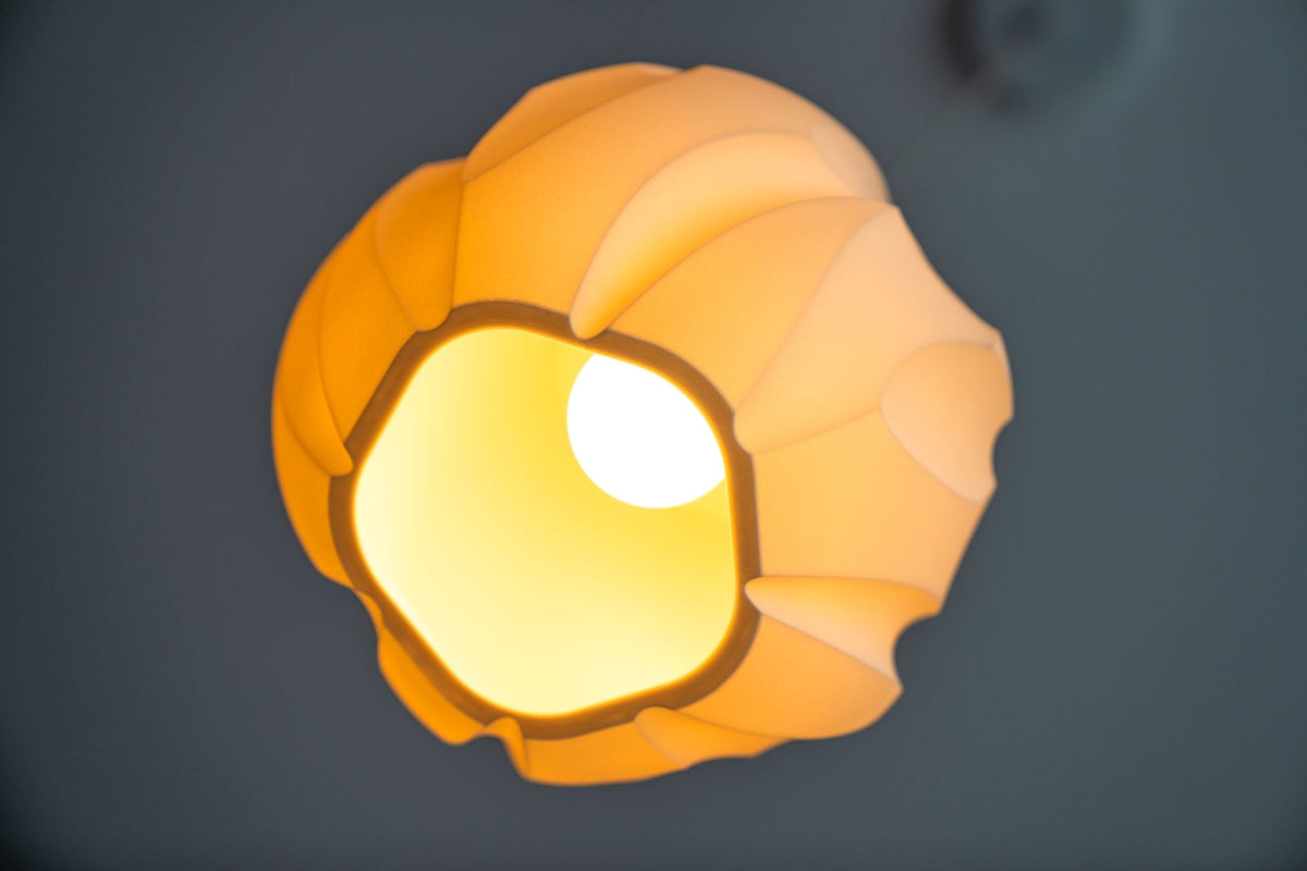 Bolvormige lampenkap van onderaf met een brandende lamp in de onregelmatige opening.