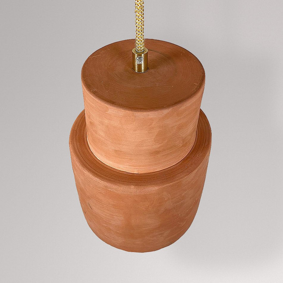 Gelaagde keramieken hanglamp in terracotta, schuin van onderen gezien.