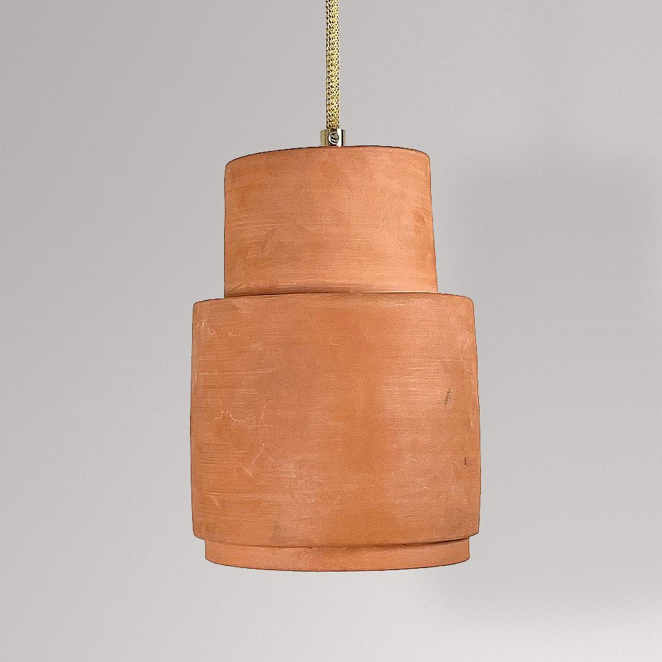 Gelaagde cilindrische keramieken hanglamp in terracotta aan een goudkleurig snoer.