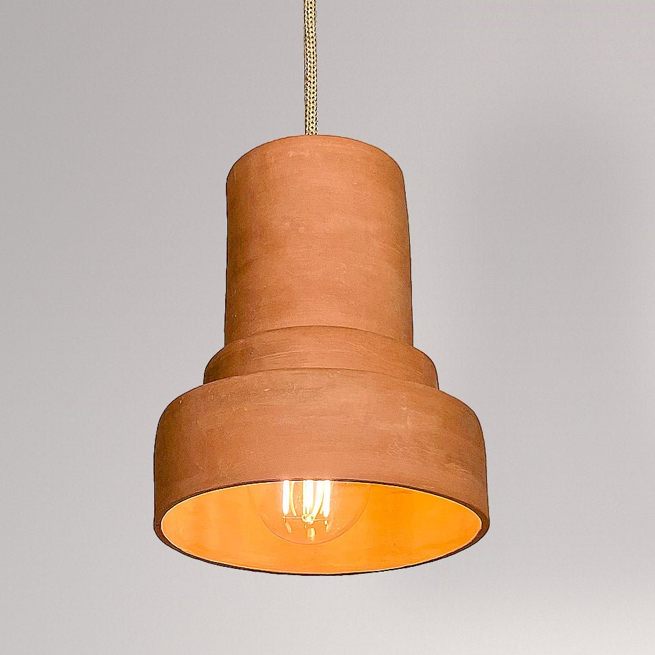 Getrapte keramieken hanglamp in terracotta met brandende lamp.