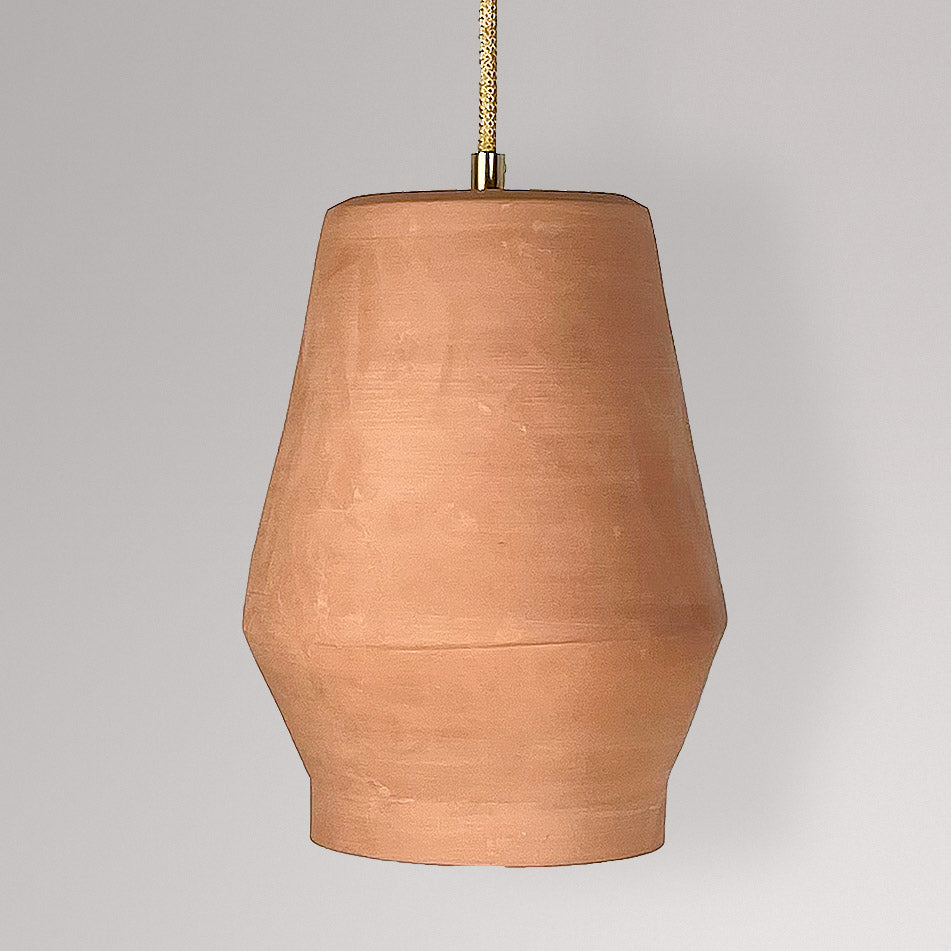 Tonvormige keramieken hanglamp in terracotta aan een goudkleurig textielsnoer.