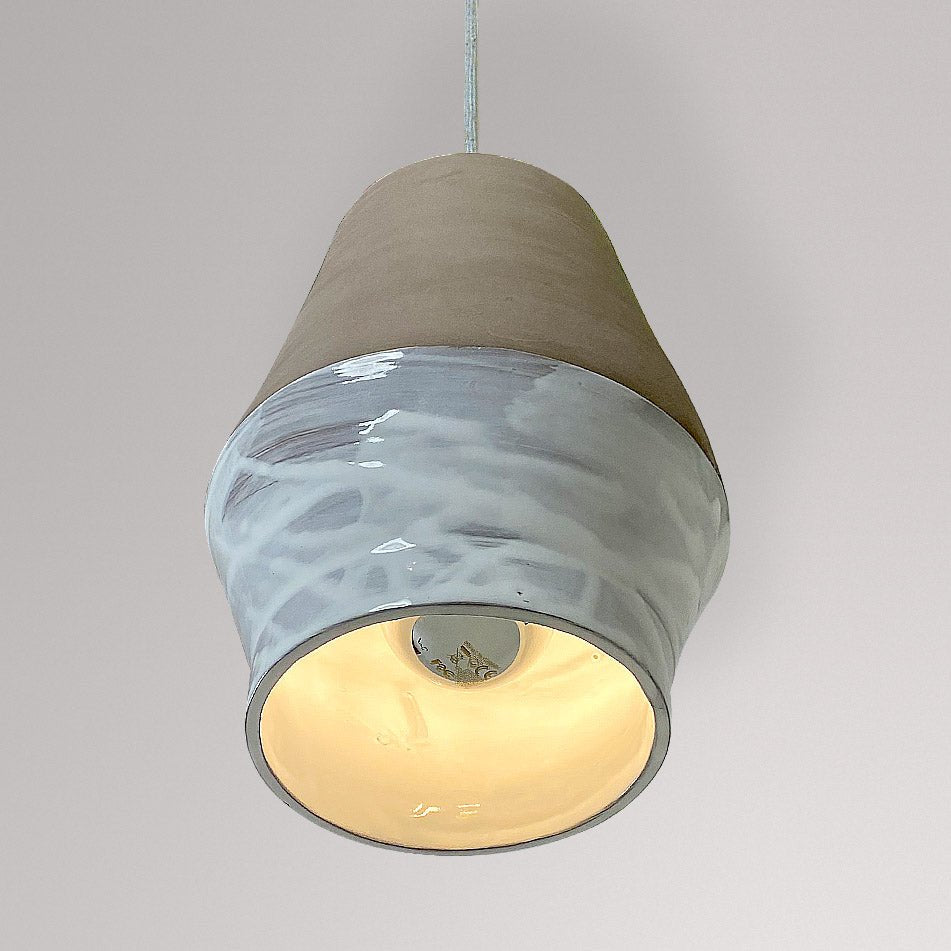 Tonvormige keramieken hanglamp met wit gemarmerd glazuur en brandende lamp.