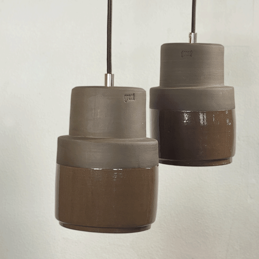 Twee keramieken hanglampen met grijze bovenkant en chocoladebruin glazuur.