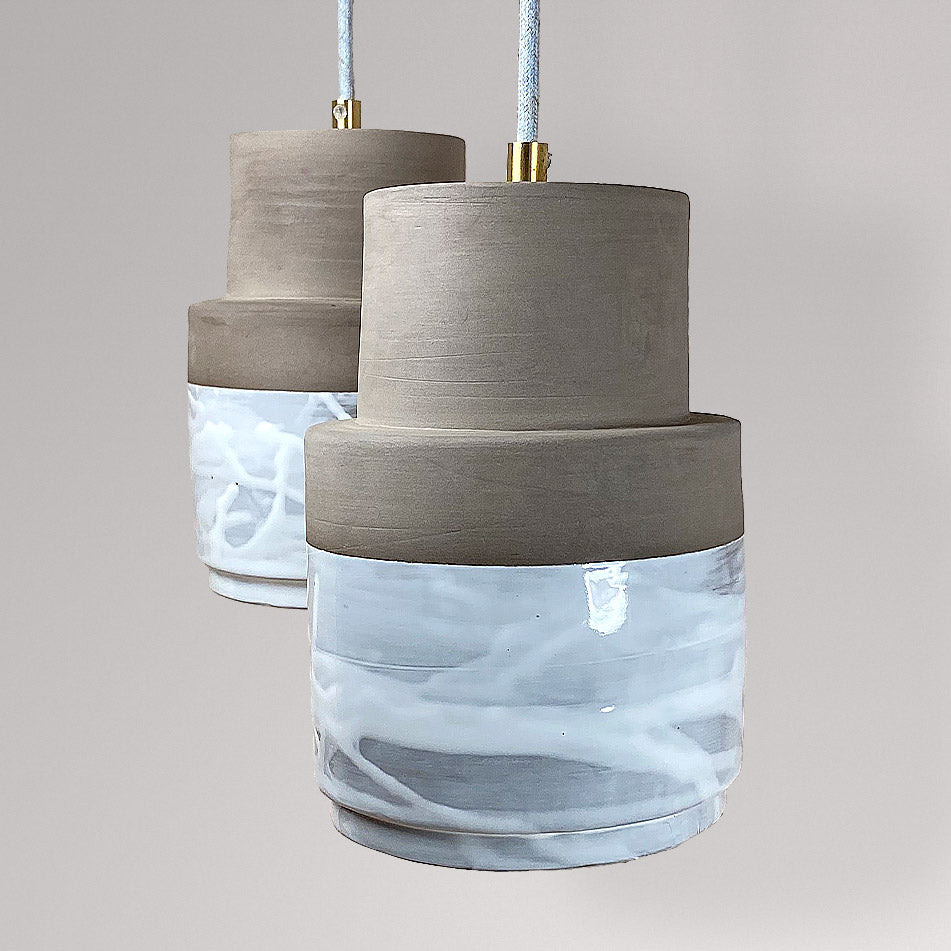 Twee keramieken hanglampen met grijze bovenkant en wit gemarmerd glazuur.